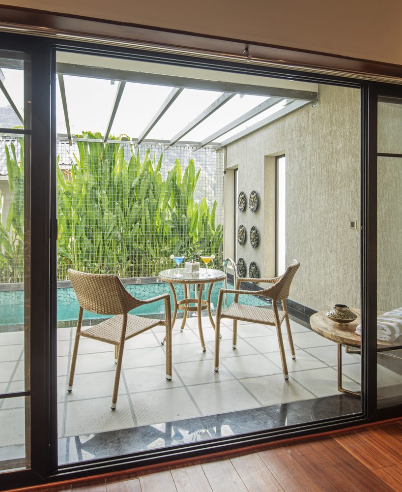 Table seating in a leafy courtyard at Samroha Resort